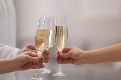 Photo of People clinking glasses of champagne against blurred background, closeup