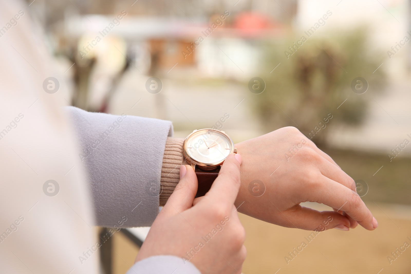 Photo of Woman with luxury wristwatch on blurred background, closeup