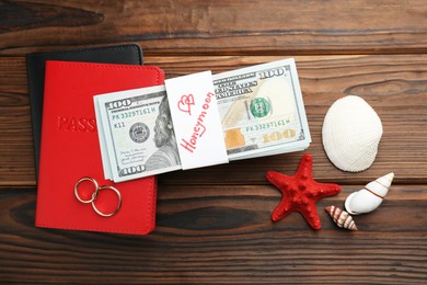 Photo of Honeymoon concept. Flat lay composition with two golden rings and money on wooden table