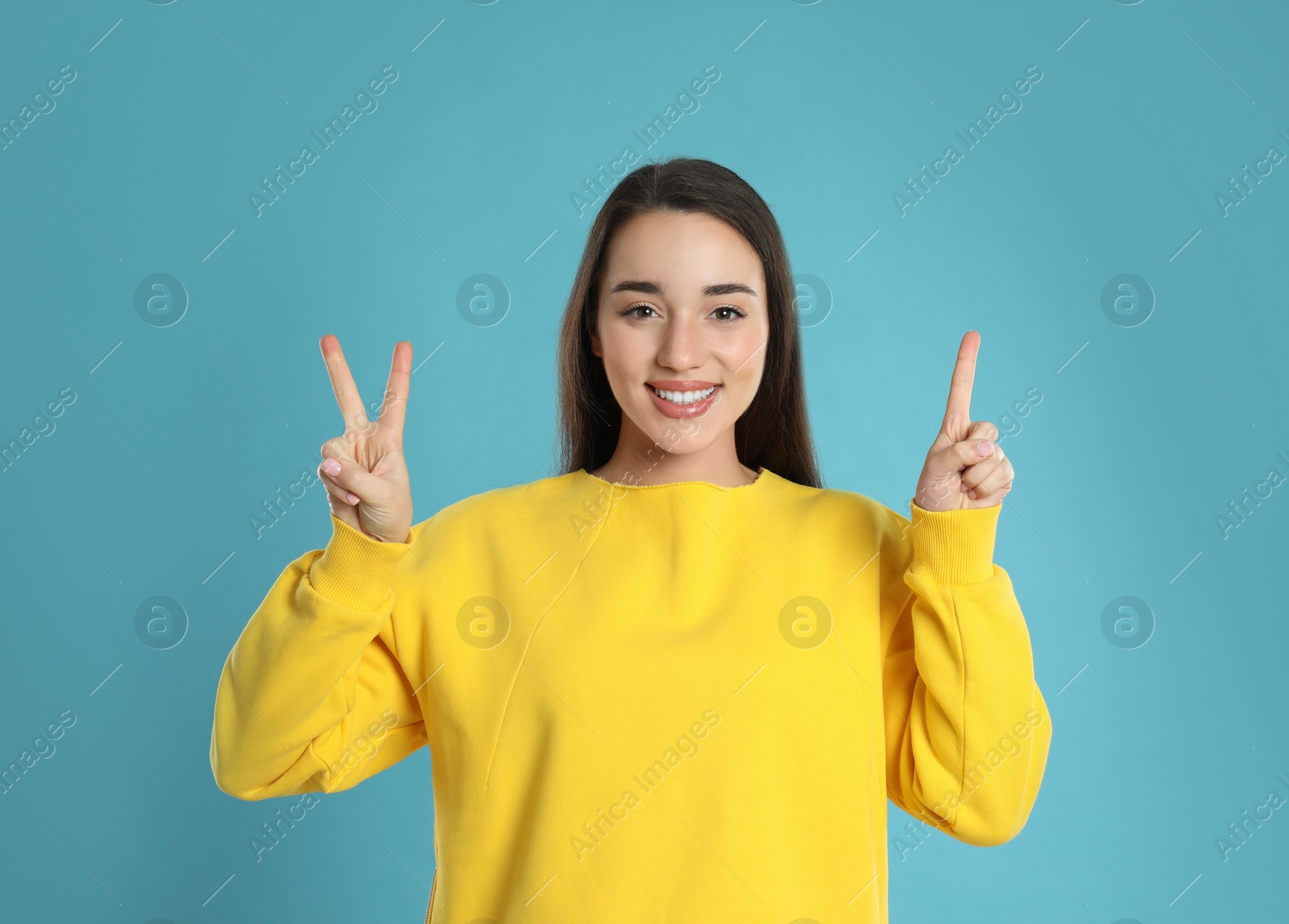 Photo of Woman showing number three with her hands on light blue background