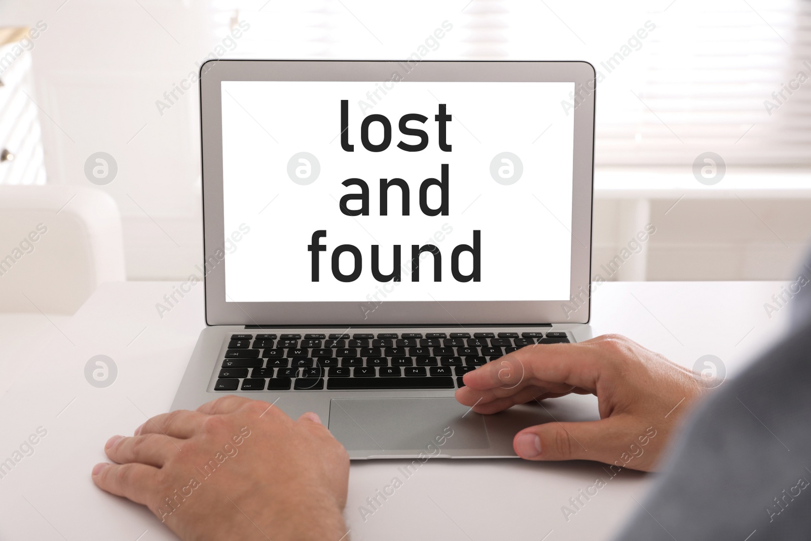 Image of Lost and Found. Man with modern laptop at white table indoors, closeup