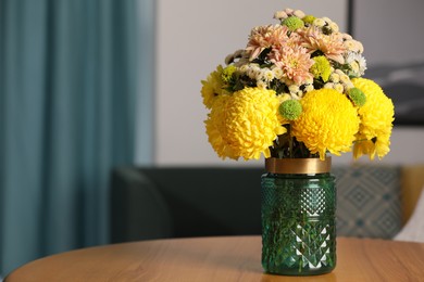 Photo of Bouquet of beautiful chrysanthemum flowers on wooden table indoors, space for text