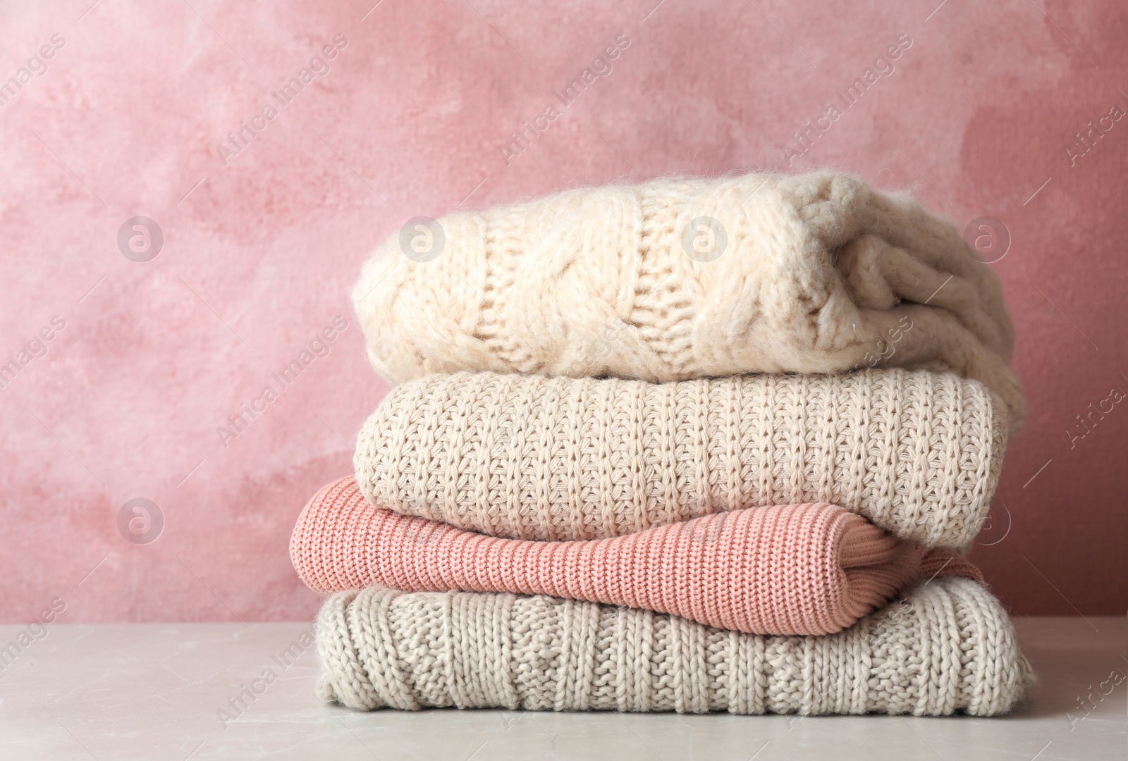 Photo of Stack of folded knitted sweaters on table. Space for text