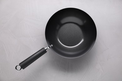 Photo of Empty iron wok on grey textured table, top view. Chinese cookware