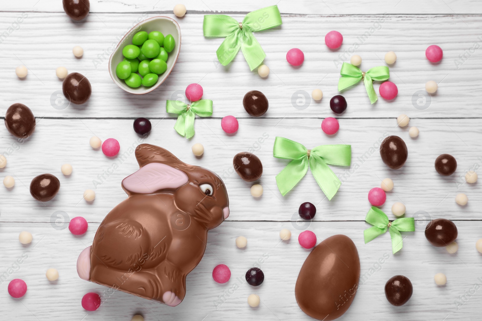 Photo of Flat lay composition with chocolate bunny on white wooden table. Easter celebration