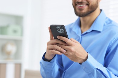 Photo of Young man using smartphone in office, closeup. Space for text