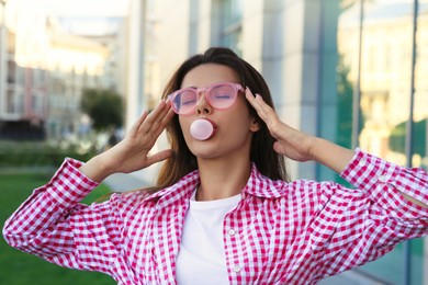 Photo of Beautiful woman in shirt blowing gum outdoors