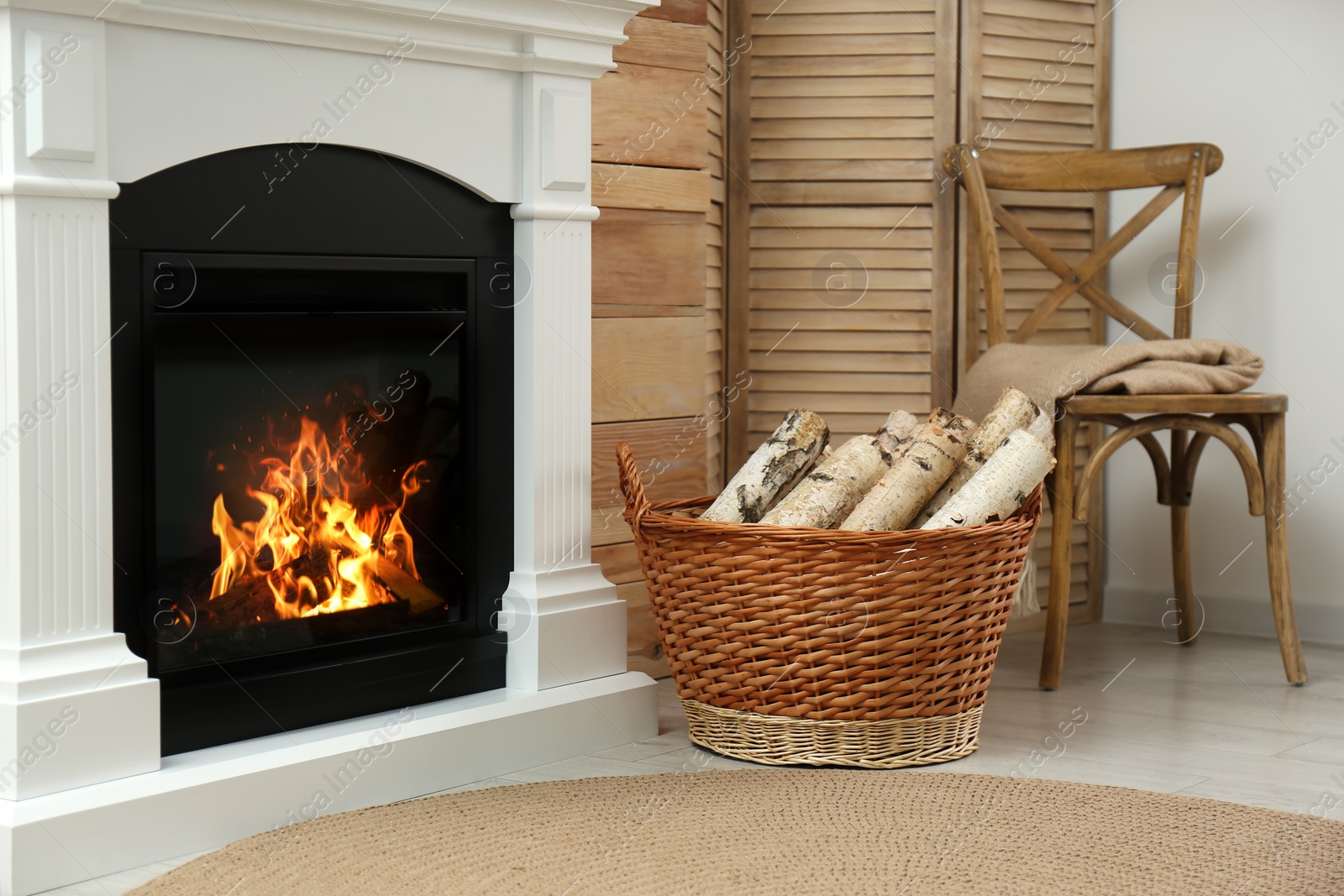 Photo of Firewood in wicker basket near fireplace indoors