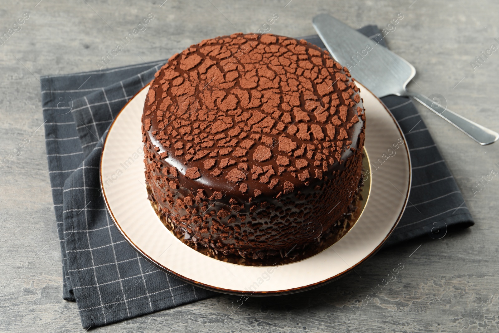 Photo of Delicious chocolate truffle cake and server on grey textured table