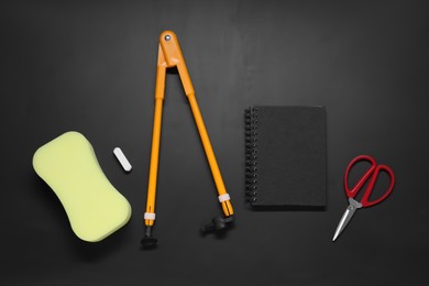 Compass, sponge, chalk, notebook and scissors on black table, flat lay