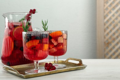 Photo of Glasses and jug of Red Sangria on white wooden table