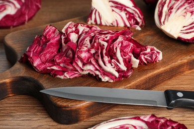 Photo of Cut radicchio and knife on wooden table, closeup
