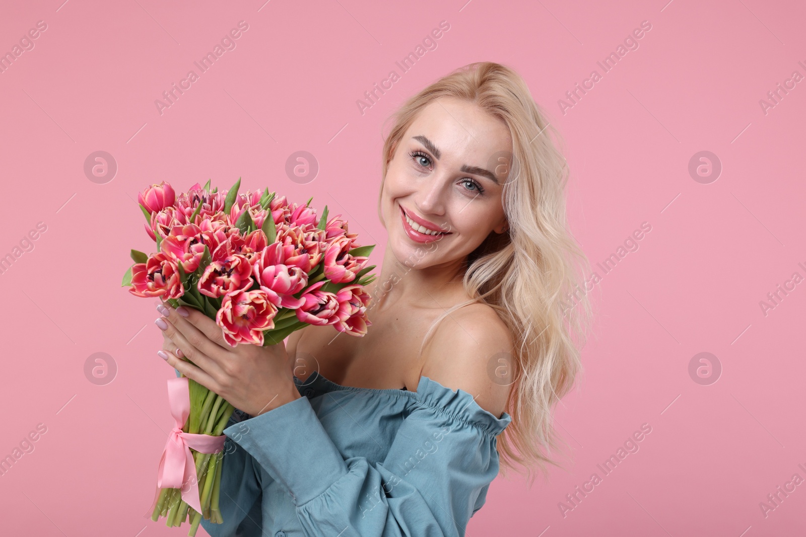 Photo of Happy young woman with beautiful bouquet on dusty pink background