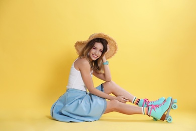 Young woman with retro roller skates on color background