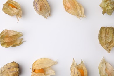 Frame of ripe physalis fruits with calyxes on white background, flat lay. Space for text