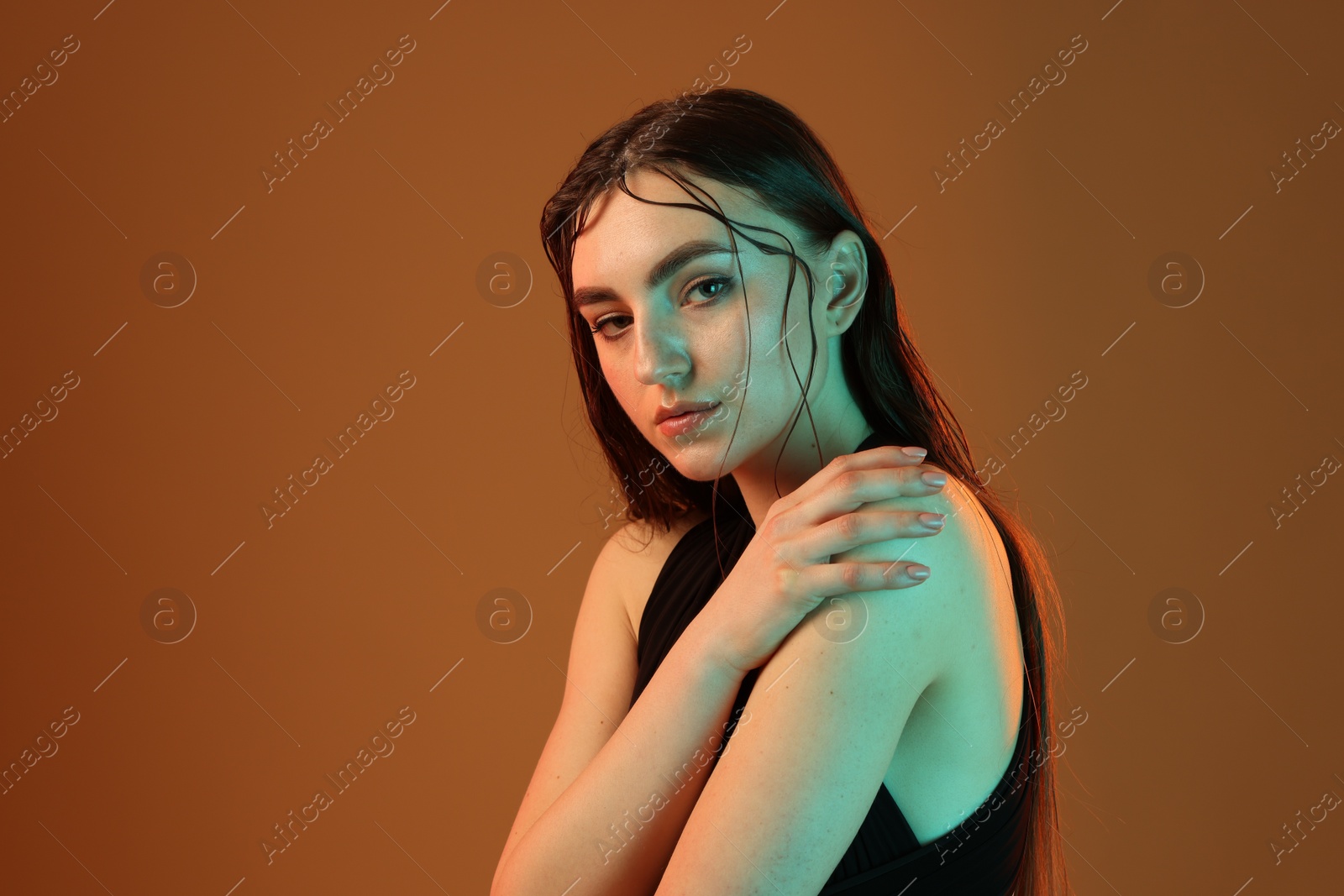 Photo of Portrait of beautiful woman in neon light on brown background