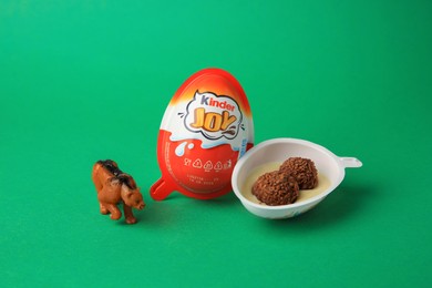 Photo of Slynchev Bryag, Bulgaria - May 25, 2023: Kinder Joy Egg with sweet candies and toy on green background
