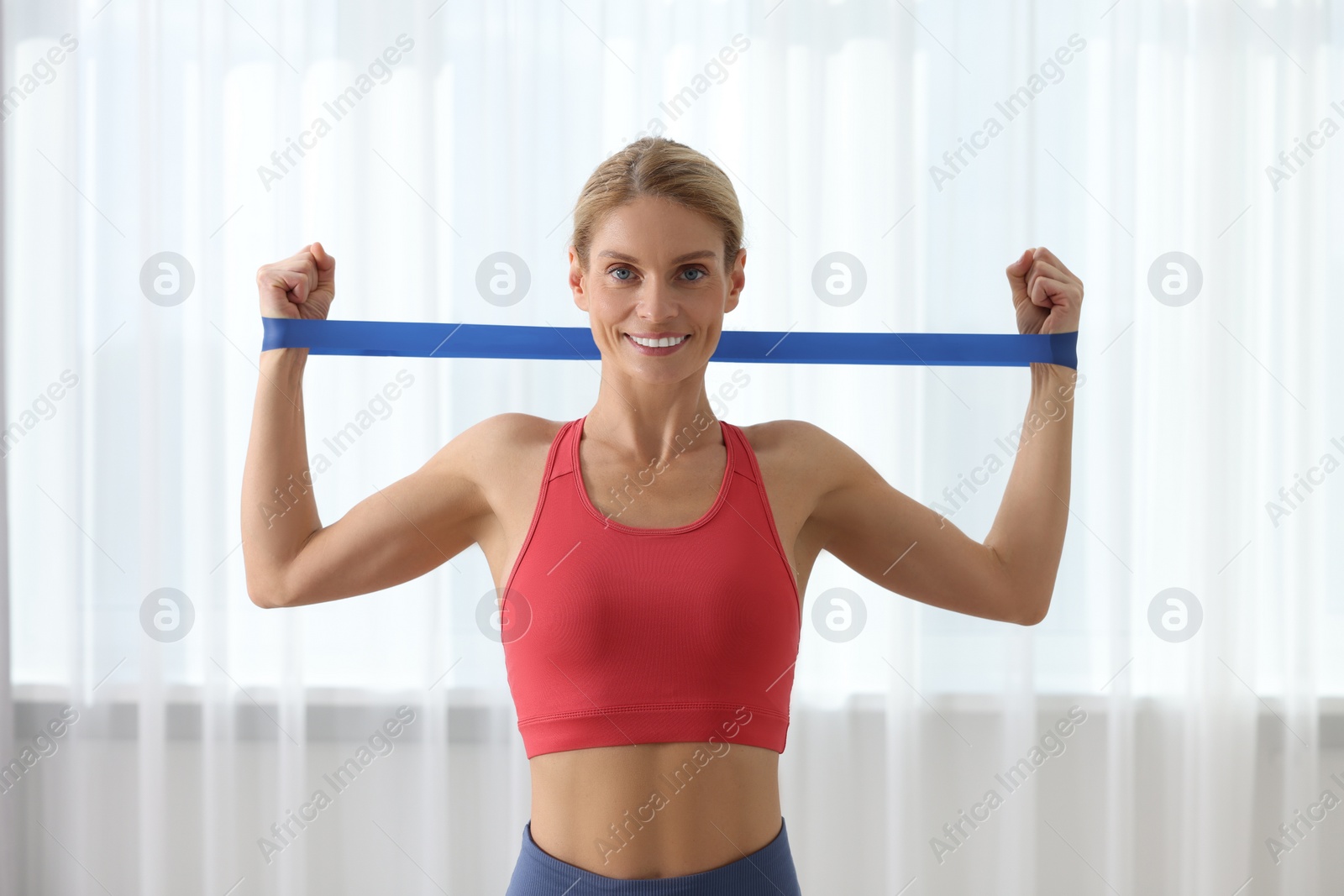 Photo of Fit woman doing exercise with fitness elastic band indoors