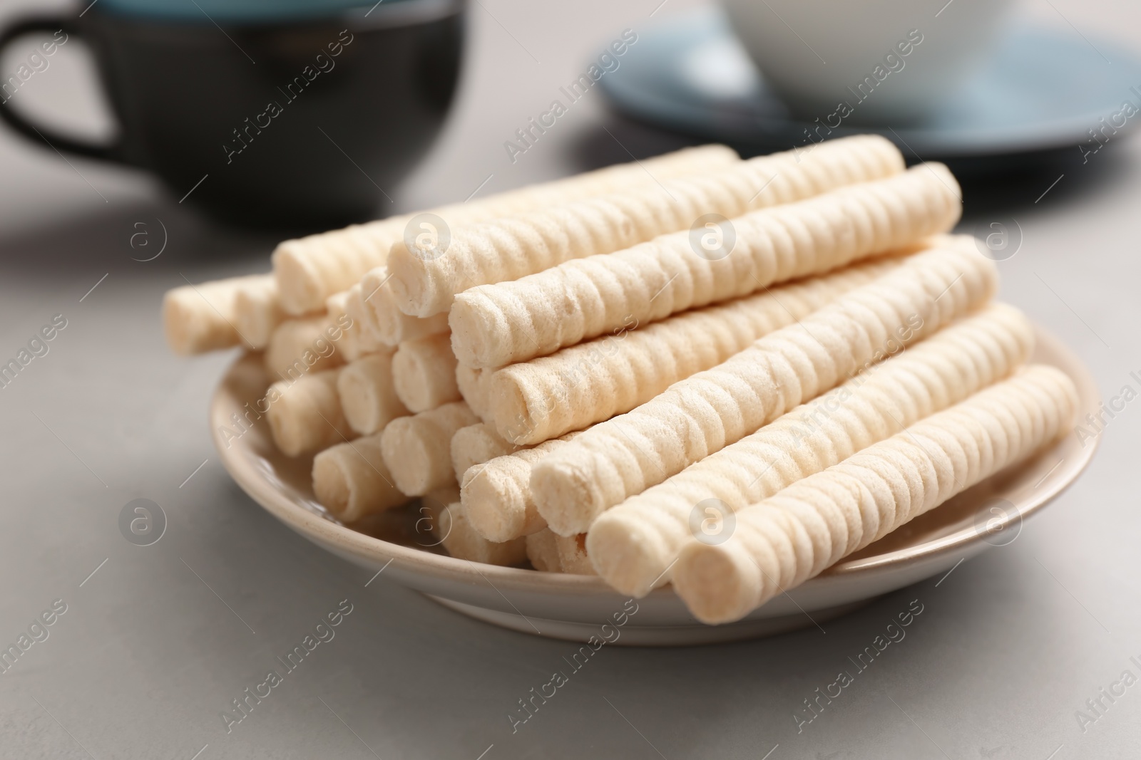 Photo of Plate with delicious wafer rolls on grey table. Sweet food