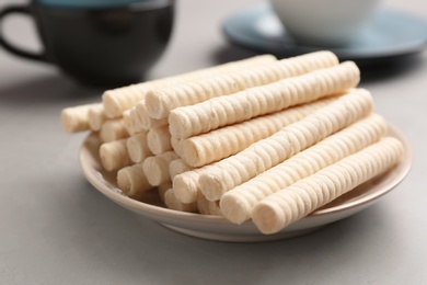 Photo of Plate with delicious wafer rolls on grey table. Sweet food