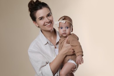 Photo of Beautiful mother with her cute baby on beige background