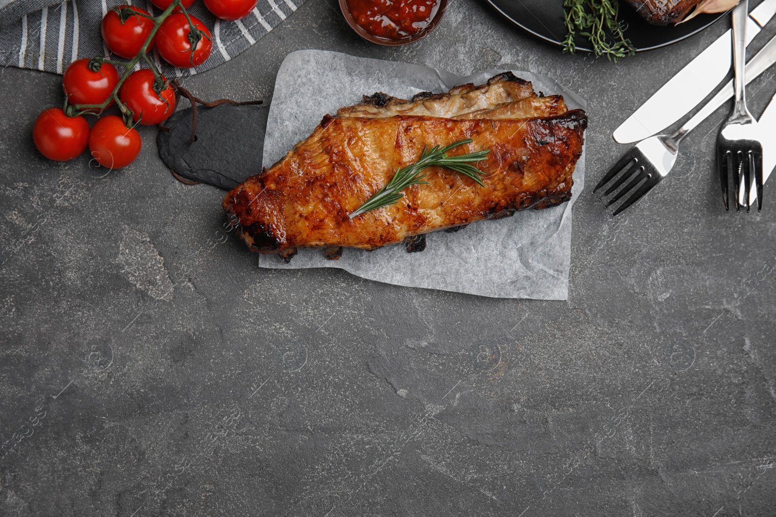 Photo of Tasty grilled ribs served on grey table, flat lay. Space for text