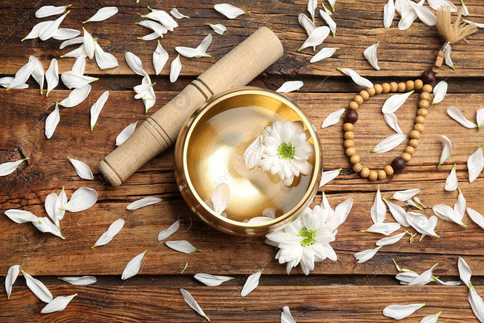 Photo of Flat lay composition with golden singing bowl on wooden table. Sound healing