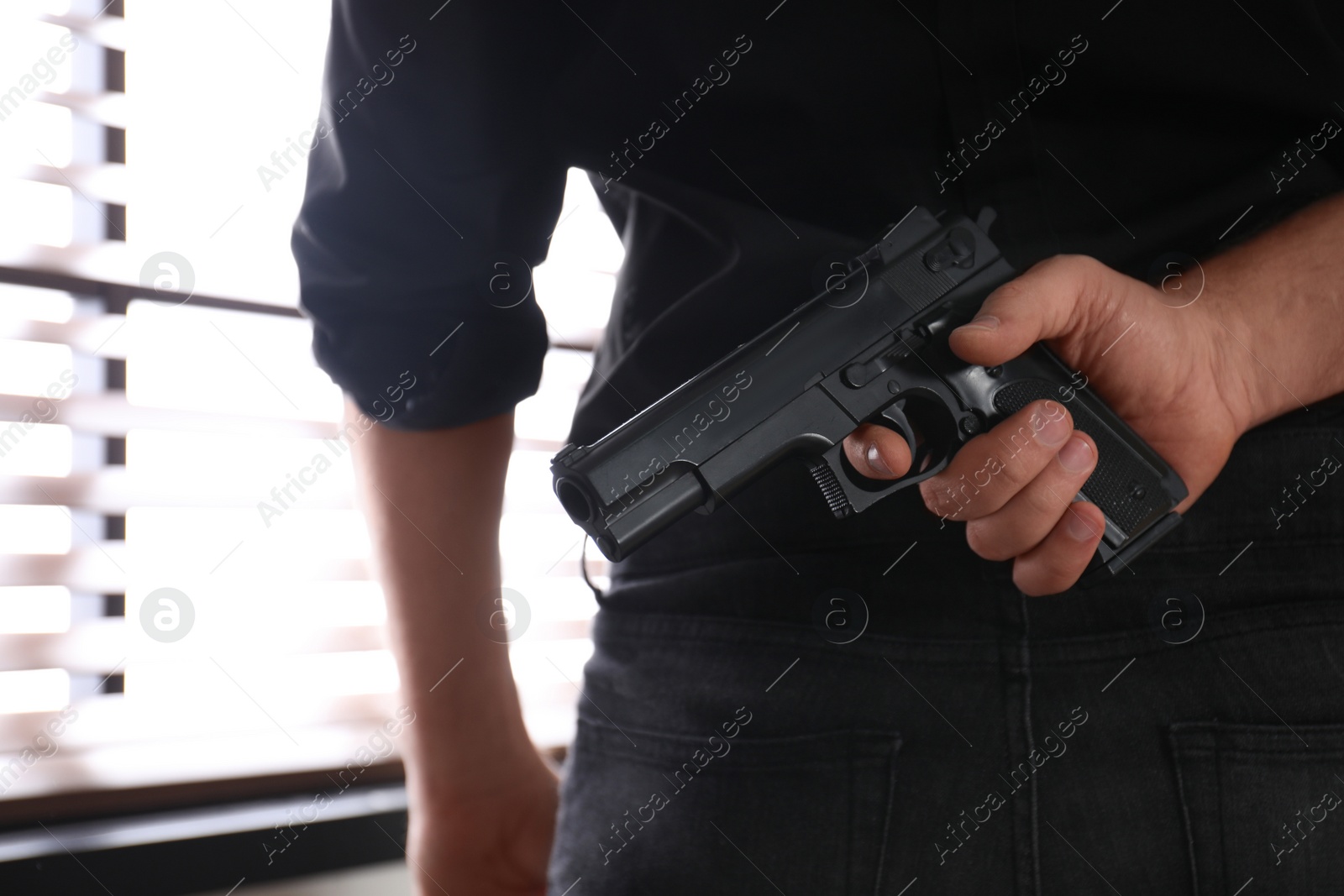 Photo of Man with gun near window indoors, closeup