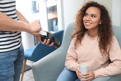 Client using credit card machine for non cash payment in cafe