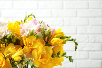 Photo of Beautiful blooming freesias against white brick wall