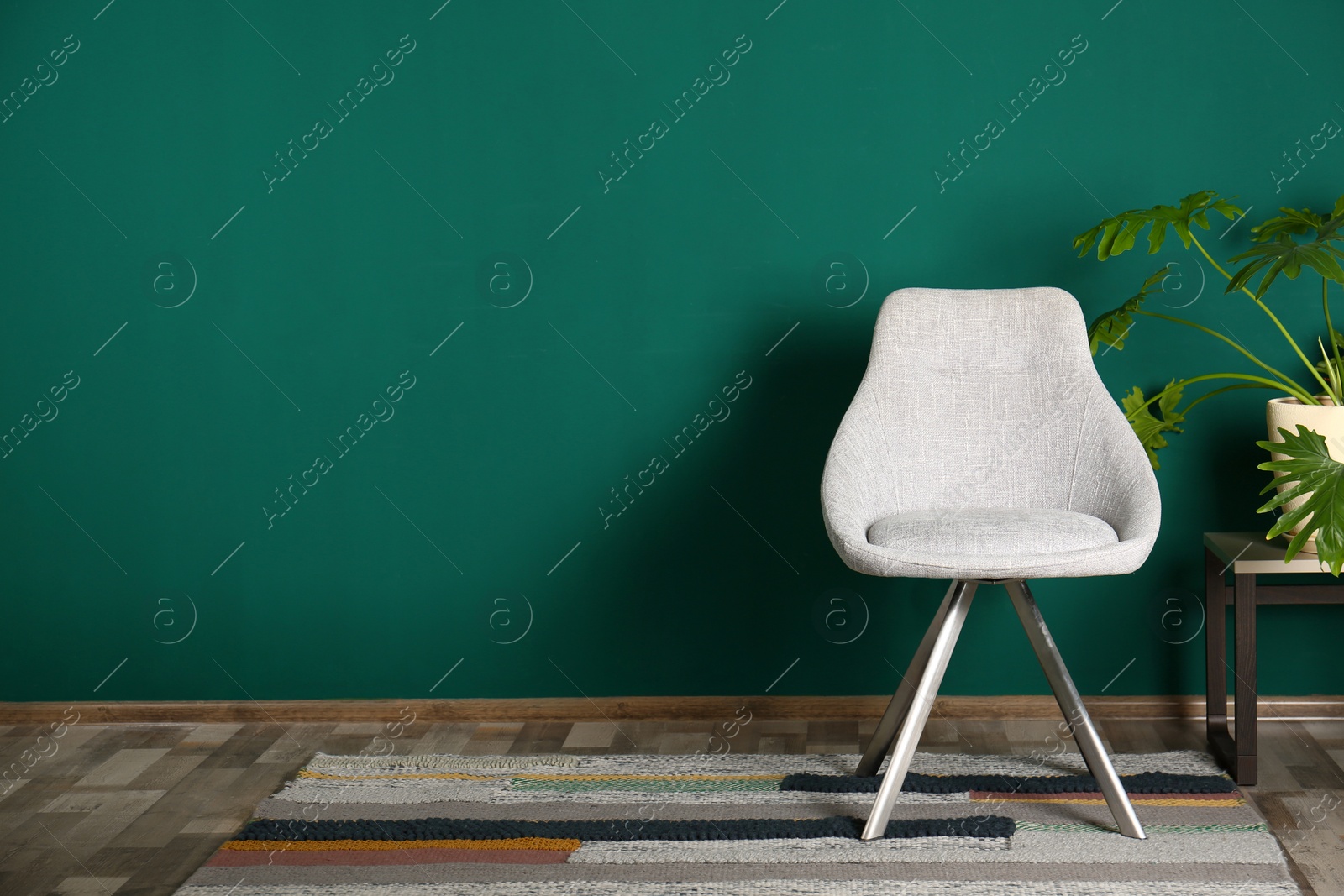 Photo of Stylish room interior with comfortable chair and plant near color wall, space for text