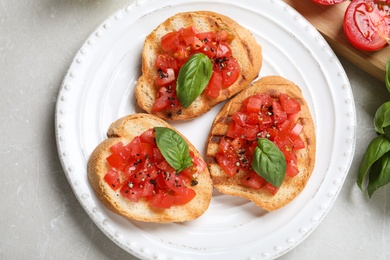 Photo of Tasty bruschettas with tomatoes on light grey marble table, flat lay