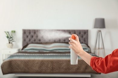 Photo of Woman spraying air freshener in bedroom