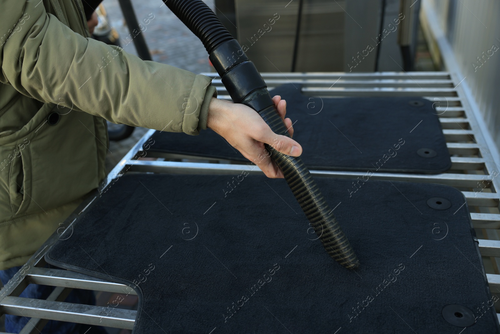 Photo of Man cleaning auto carpets with vacuum cleaner at self-service car wash, closeup