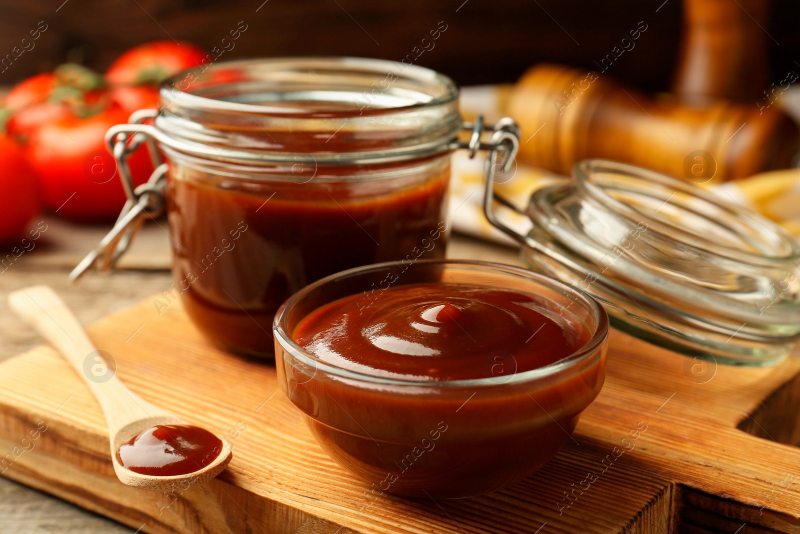 Photo of Tasty barbeque sauce in bowl, jar and spoon on wooden table, closeup