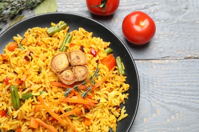 Photo of Tasty rice pilaf with vegetables on grey wooden table, flat lay