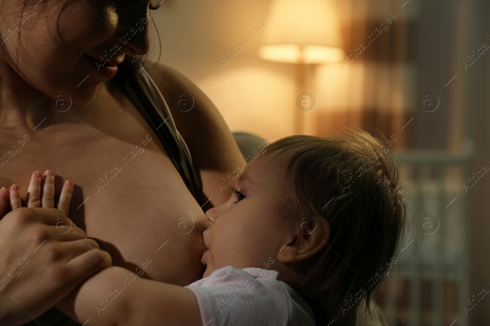 Photo of Woman breastfeeding her little baby at home, closeup