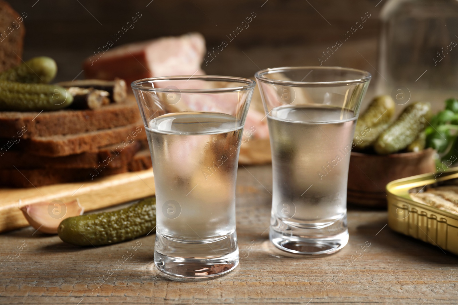 Photo of Cold Russian vodka with snacks on wooden table, closeup