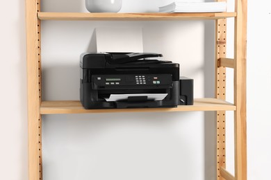 Photo of Modern printer with paper on wooden shelf in home office