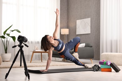 Happy sports blogger recording fitness lesson with camera at home