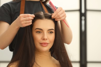 Photo of Hair styling. Professional hairdresser working with client in salon, closeup. Space for text