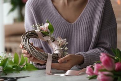 Female decorator creating beautiful wreath at table