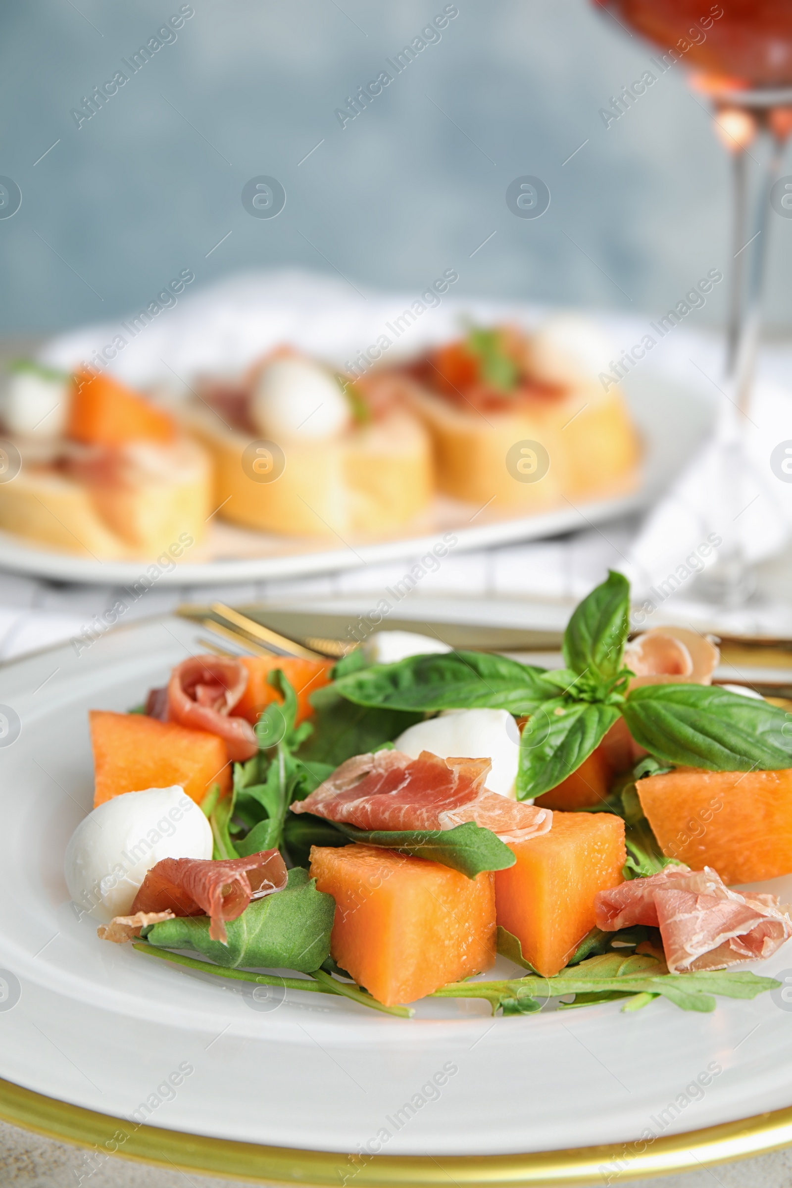 Photo of Fresh melon with prosciutto, mozzarella and basil on plate, closeup