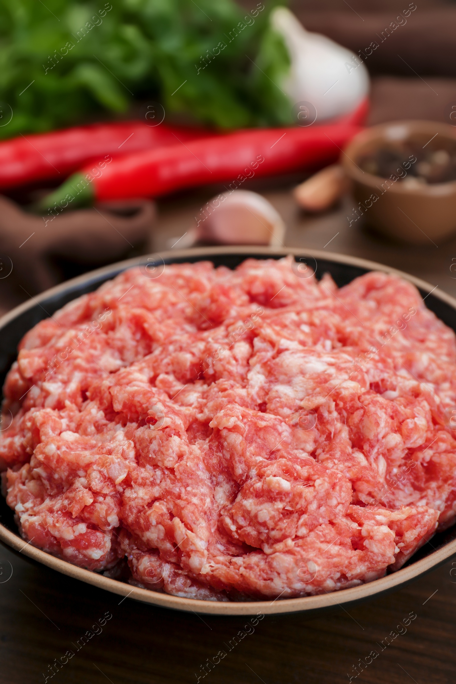 Photo of Bowl with raw fresh minced meat on wooden table, closeup