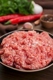 Bowl with raw fresh minced meat on wooden table, closeup