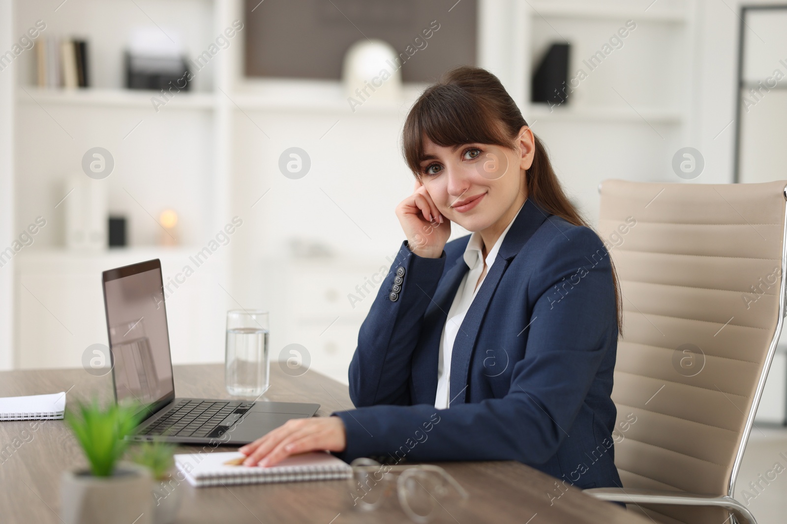 Photo of Woman watching webinar at wooden table in office