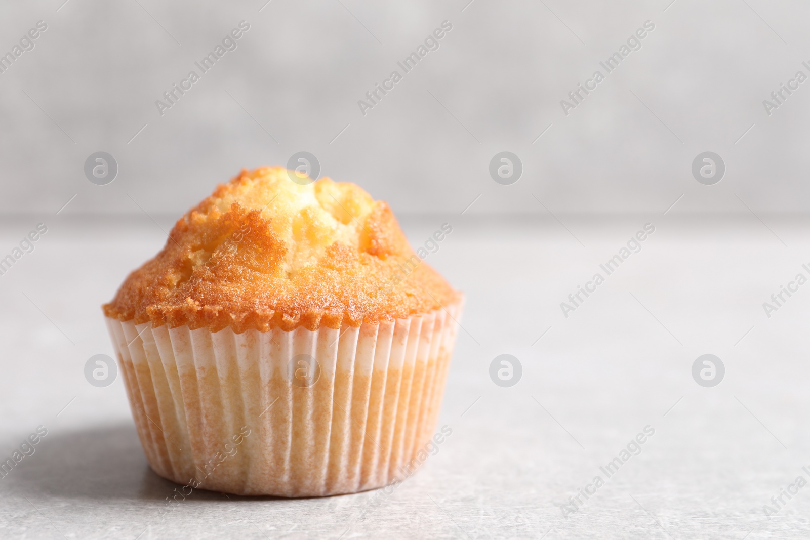 Photo of Tasty muffin on light grey table, closeup. Space for text