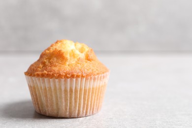 Photo of Tasty muffin on light grey table, closeup. Space for text