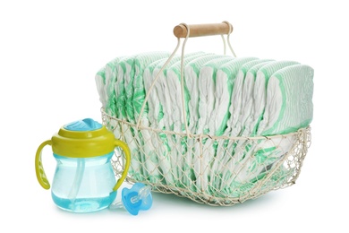 Photo of Basket with disposable diapers and baby accessories on white background