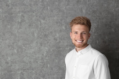 Photo of Portrait of handsome young man near grey wall. Space for text